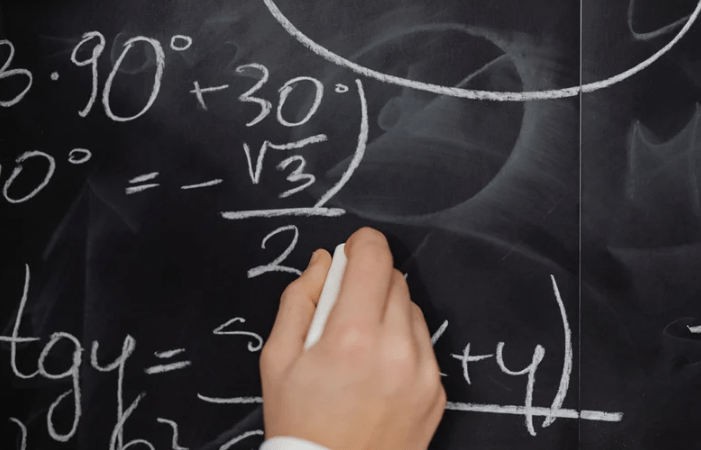 Gambar mahasiswa jurusan Matematika sedang mengerjakan soal di papan tulis dengan laptop.